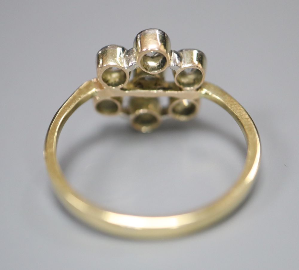 A 750 yellow metal and seven stone diamond cluster flower head ring, size L, gross 3.3 grams.